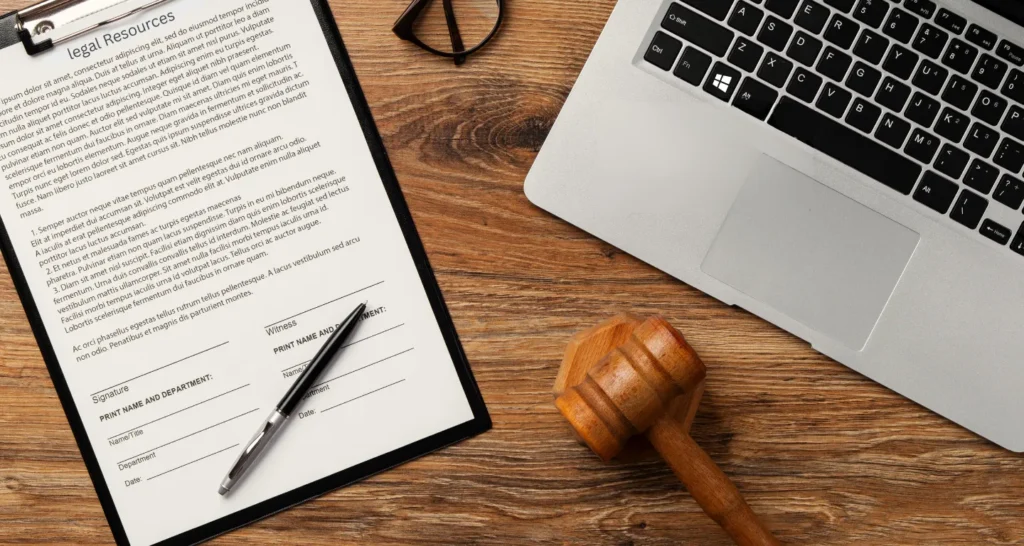 Legal resource form on a clipboard beside a laptop, pen, gavel, and glasses on a wooden desk, symbolizing how location scouting software streamlines access to film permits and legal documentation.