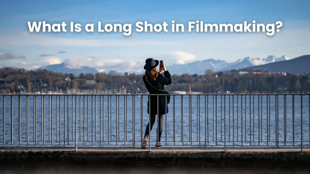 Woman taking a photo by a lake with snowy mountains in the distance, illustrating long shot framing and spatial storytelling in filmmaking