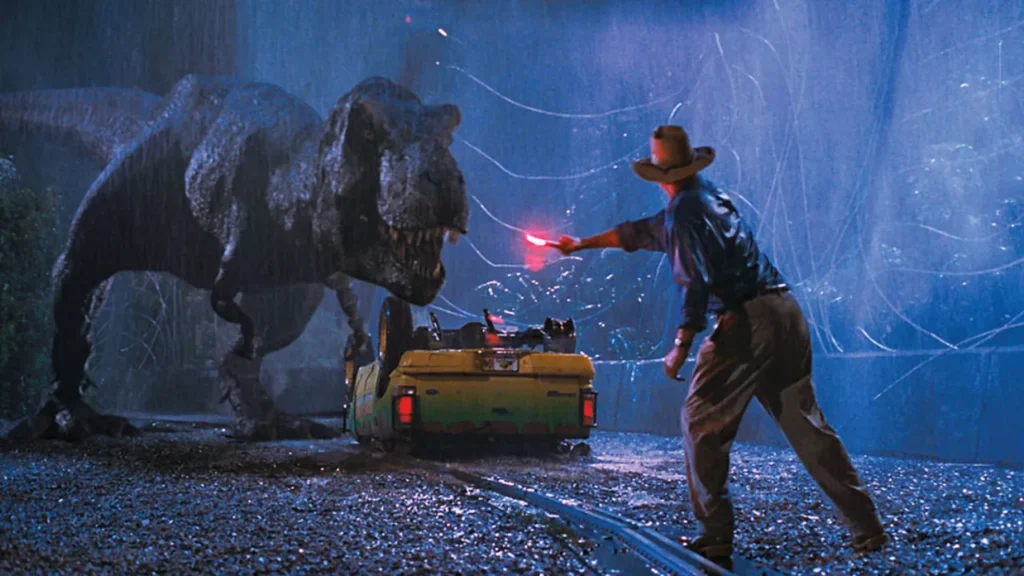 Scene from Jurassic Park (1993) featuring a lifelike T-Rex approaching a man with a flare in the rain, showcasing the revolutionary blend of animatronics and computer-generated imagery in film.